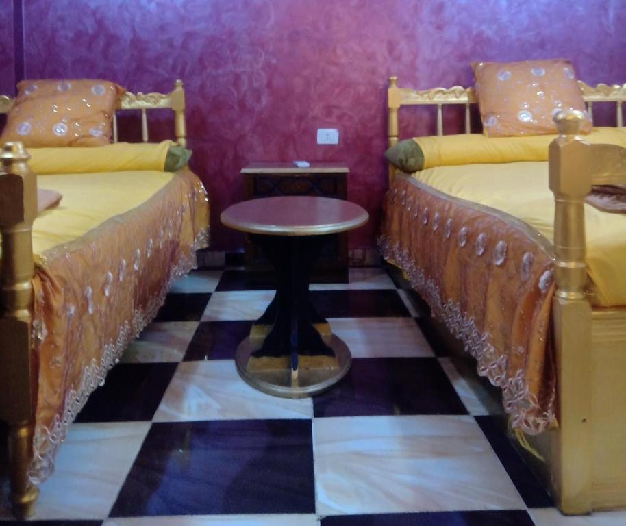 a room with two beds with a table between them at App11- BELAL - Enjoy the privacy of staying in a quiet apartment with free Wi-Fi as your complete second home in the heart of Hurghada in Hurghada