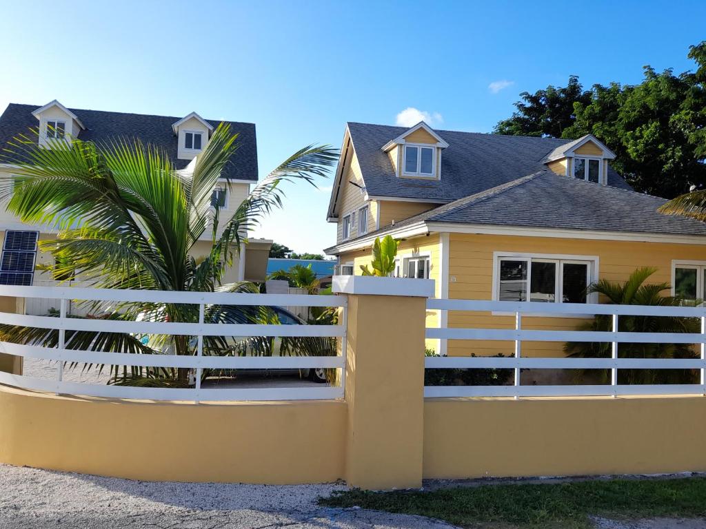 a white fence in front of a yellow house at Villa By The Bay in Nassau