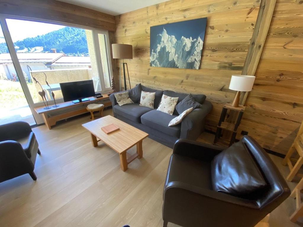 拉克吕萨Appartement 2 pièces ensoleillé avec Wi-Fi et parking, La Clusaz - FR-1-459-76的客厅里有一张沙发和一张桌子。