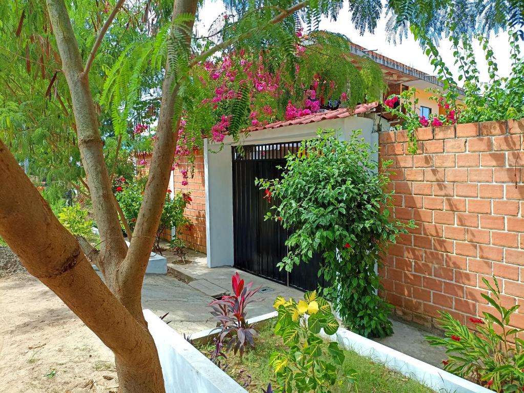 une clôture en briques avec une porte noire ornée de fleurs dans l'établissement Bijao Hostel, à Tarapoto