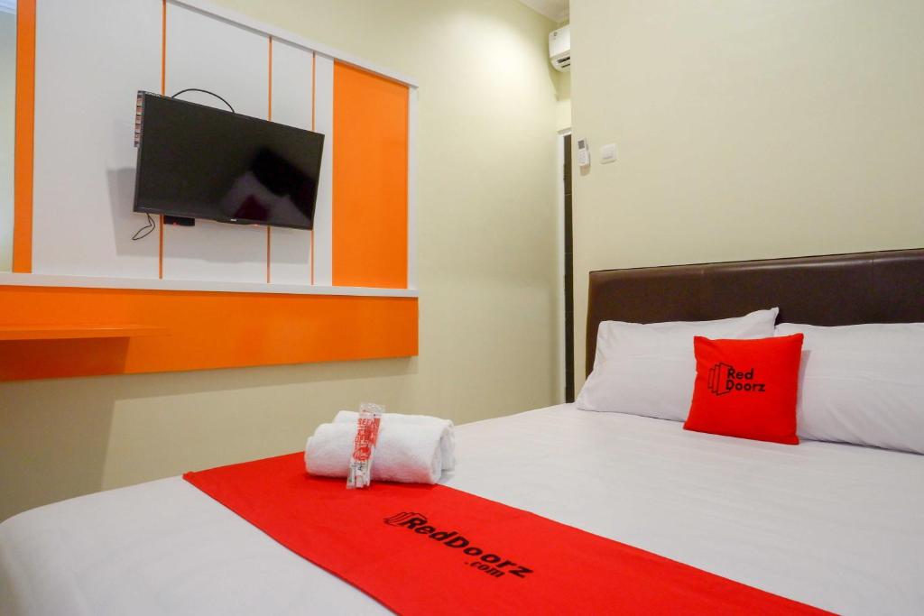 JomblangにあるRedDoorz Syariah at Kelud Sampangan Semarangの赤い毛布と薄型テレビ付きのベッドが備わるホテルルームです。
