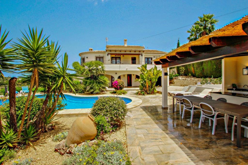 a house with a pool and a table and chairs at Nessa - well furnished villa with panoramic views in Benitachell in Benitachell