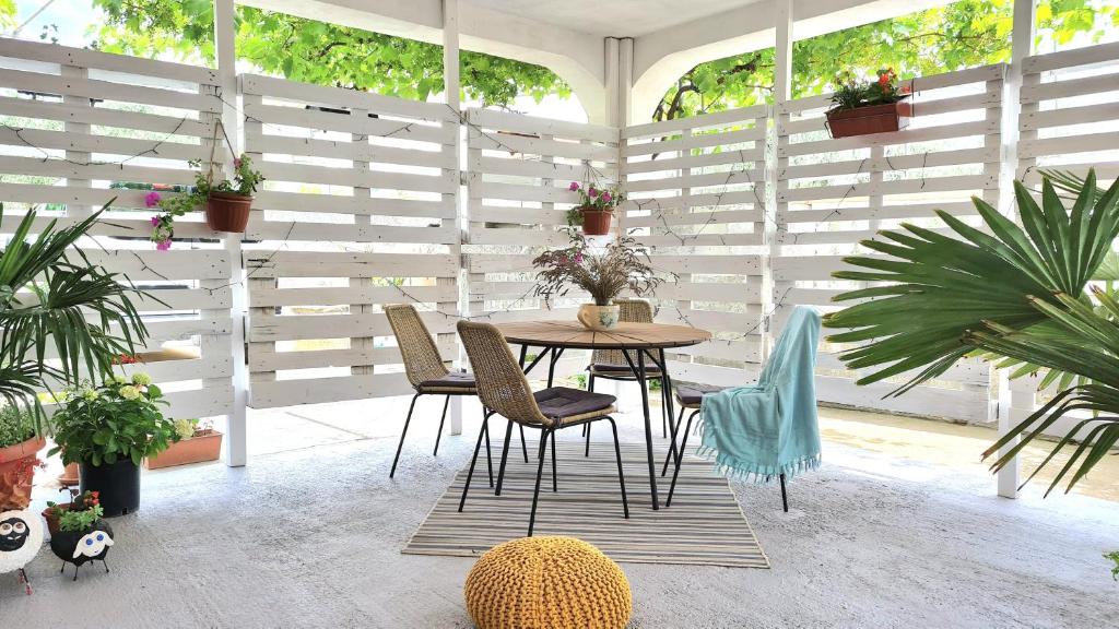 una mesa y sillas en una habitación con plantas en Apartman Ivan Šibenik - Brodarica, en Brodarica