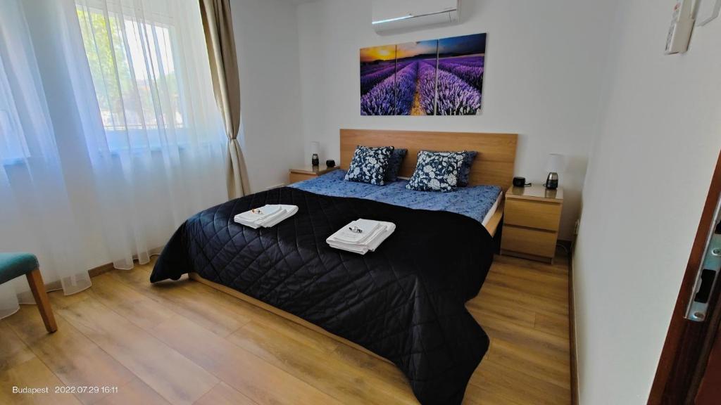 a bedroom with a bed with a black comforter at Paskal-Lux Apartments with Free Parking and AC in Budapest