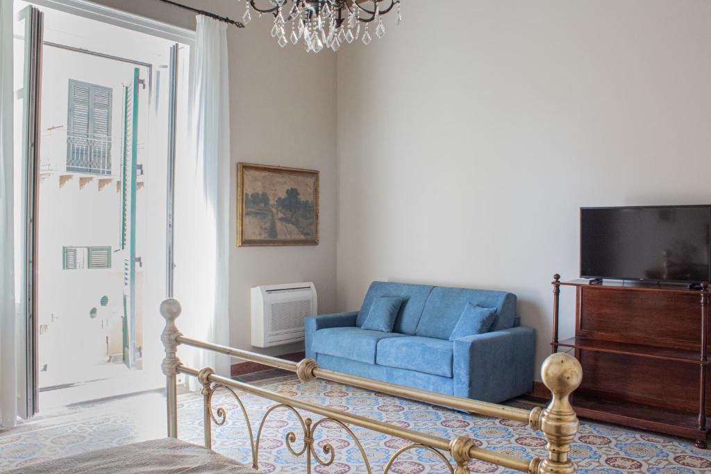 una silla azul en la sala de estar con TV en Dimora Lecerf, en Palermo