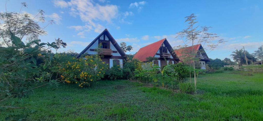 una casa con techo rojo en un campo en Chalé à 300 m da praia Rasa, com horta orgânica, en Búzios