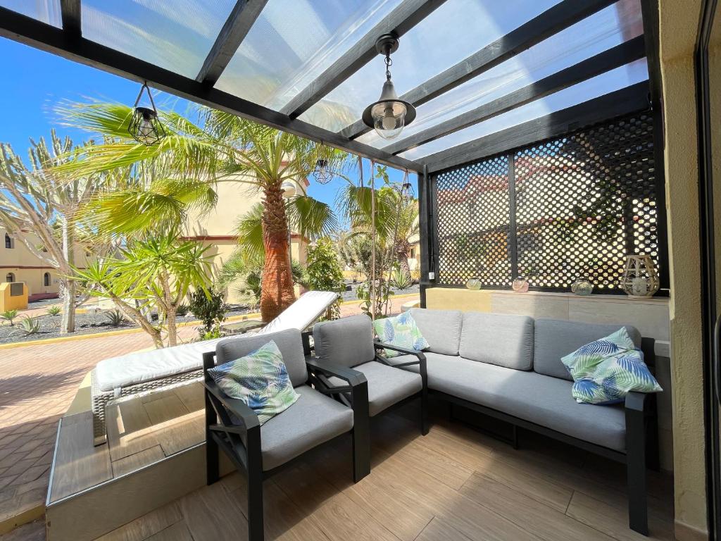 un patio con sofá, sillas y palmeras en AGPI Fuerteventura Apartments Internet Fibra WIFI GRATIS, en Costa Calma