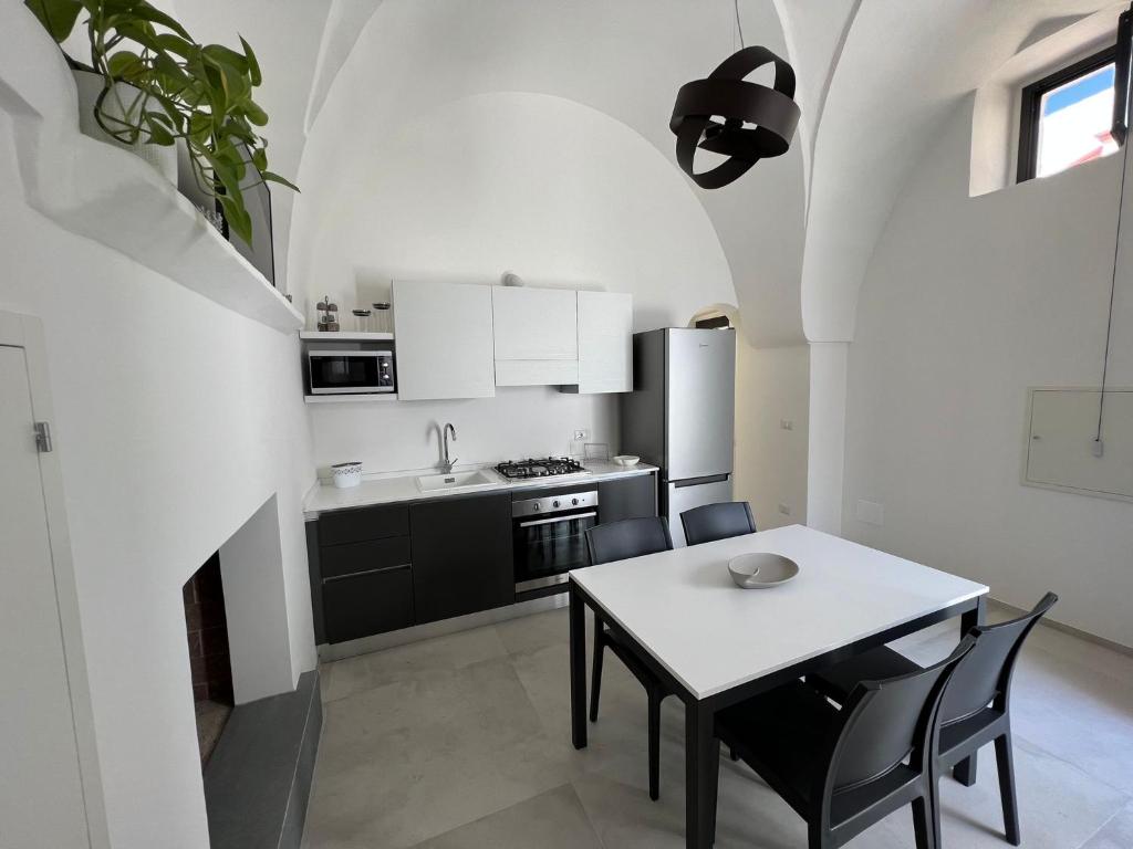 una cucina con tavolo e una cucina con armadietti bianchi di Le dimore del salento appartamento 2 a Tricase