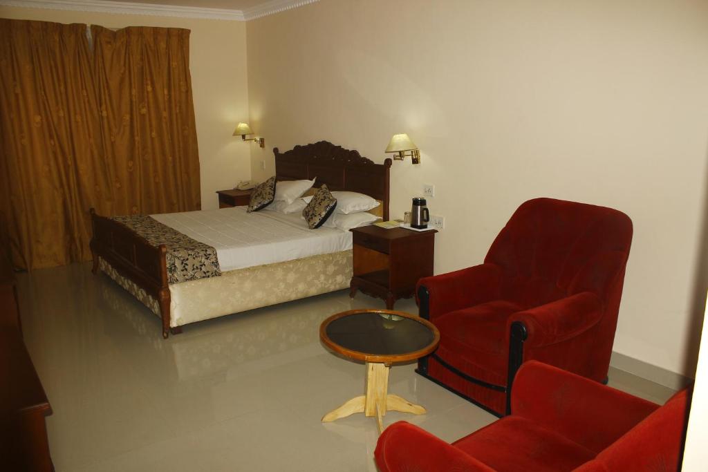 sypialnia z łóżkiem i czerwonym krzesłem w obiekcie hotel bessota international w mieście Thiruvalla