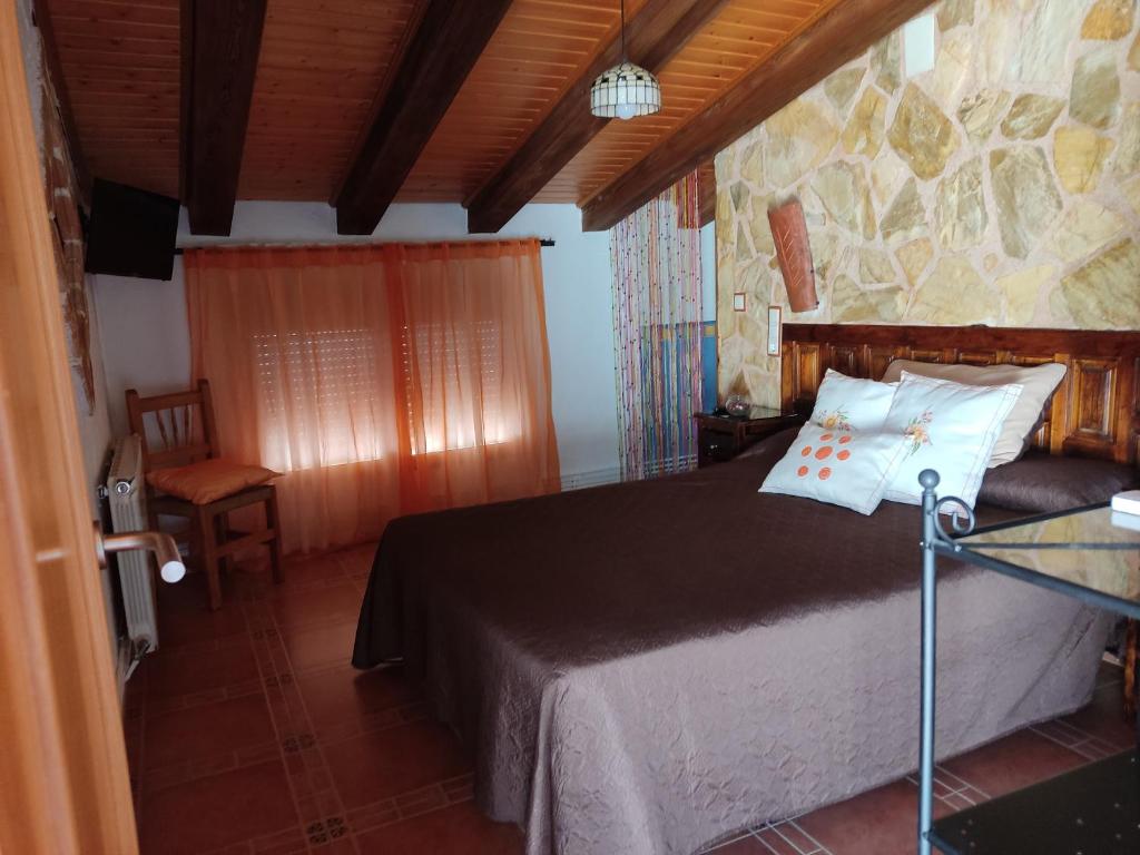 1 dormitorio con cama y pared de piedra en Rincón de Morote, en Molinicos