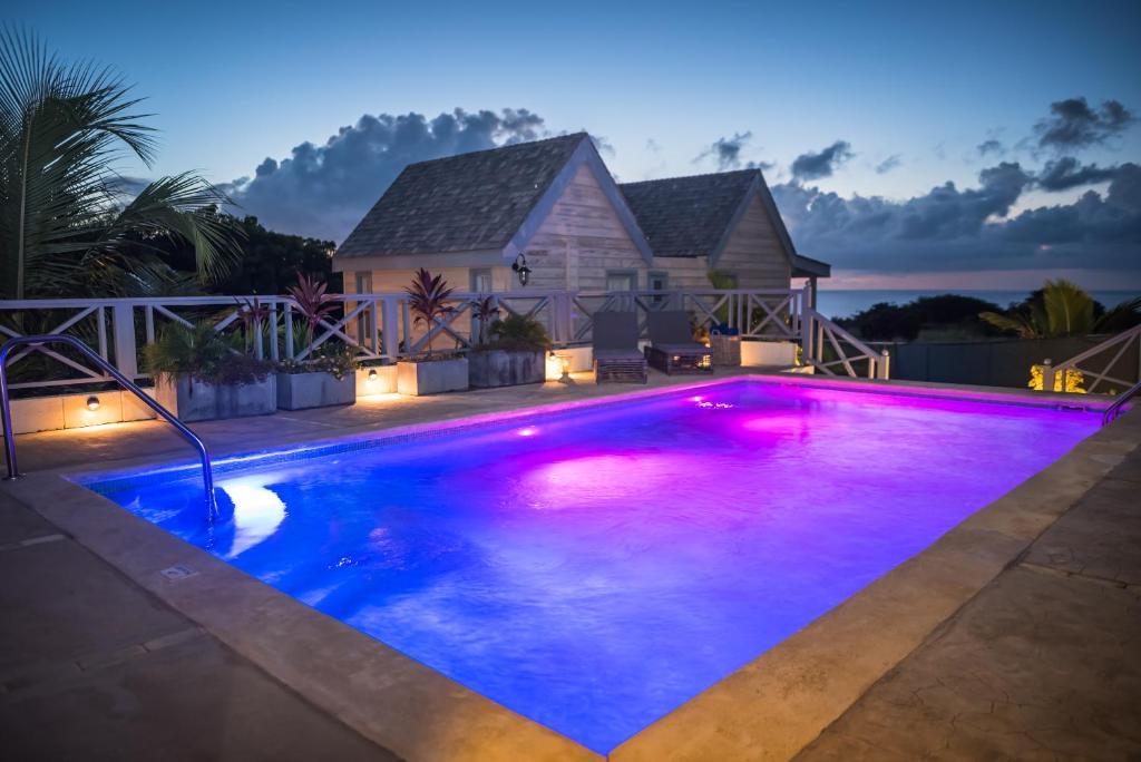 a swimming pool with purple lights in front of a house at West Rock Villas in Saint James