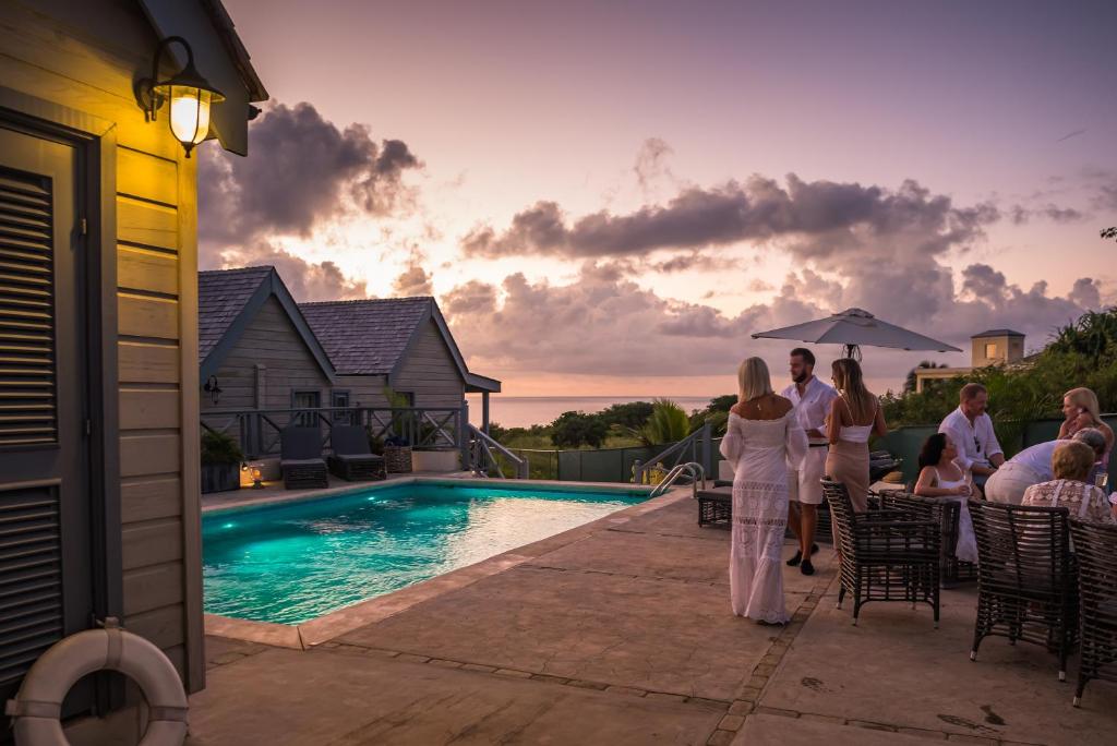 a group of people standing next to a swimming pool at West Rock Villas in Saint James