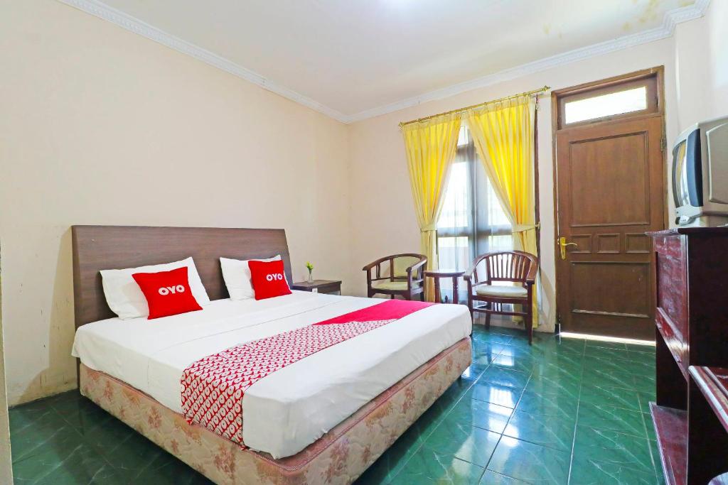 a bedroom with a bed with red pillows and a television at Super OYO 90382 Hotel Sarah Sukabumi in Wanasari