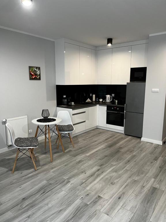 a kitchen with white cabinets and a table and chairs at Apartment Comfort in Bartoszyce