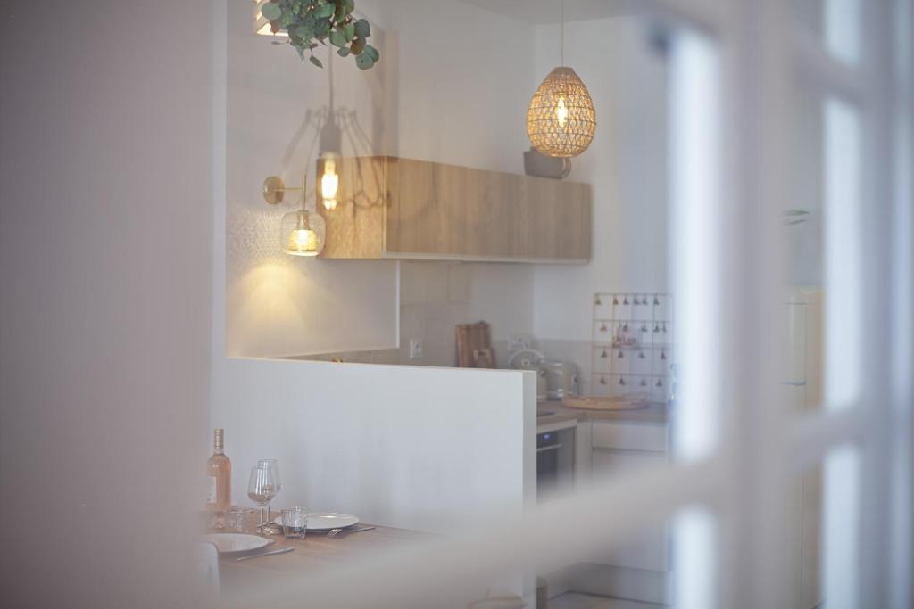 a white kitchen with a table and a mirror at La Ciotat AUTHENTIQUE - T3 à 2 pas du port et des plages - Parking souterrain offert in La Ciotat