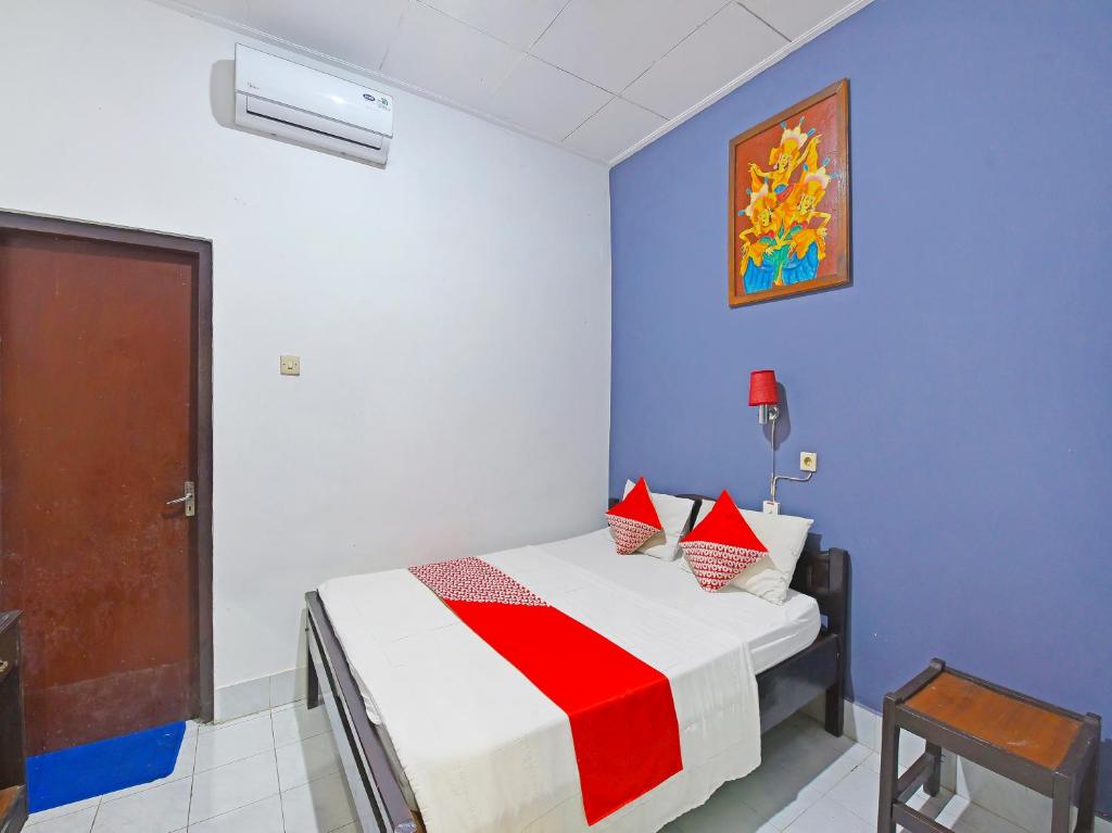 1 dormitorio con 1 cama con manta roja y blanca en OYO 3244 Grand Chandra Hotel, en Denpasar