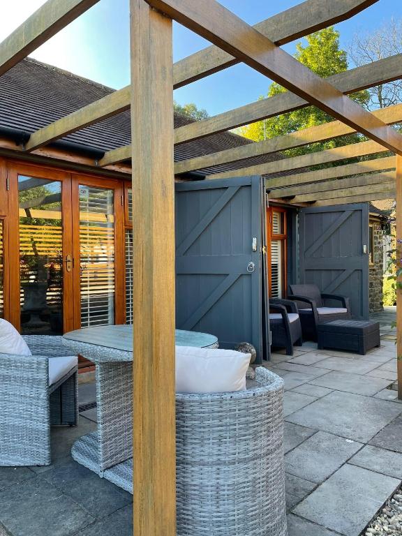 un patio con pérgola de madera, mesas y sillas en Lavender Cottage - Hillside Holiday Cottages, Cotswolds, en Warmington