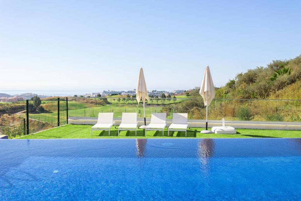 een zwembad met witte stoelen en parasols bij Luxury Penthouse Large Terrace 2 Bedrooms OR79 by AORASTAY in La Cala de Mijas