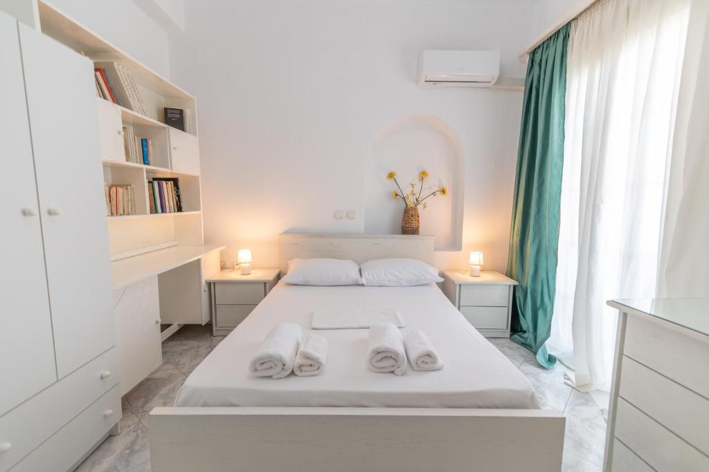 a white bedroom with a bed with two white shoes on it at Evangelia's Mansion in Naxos Chora