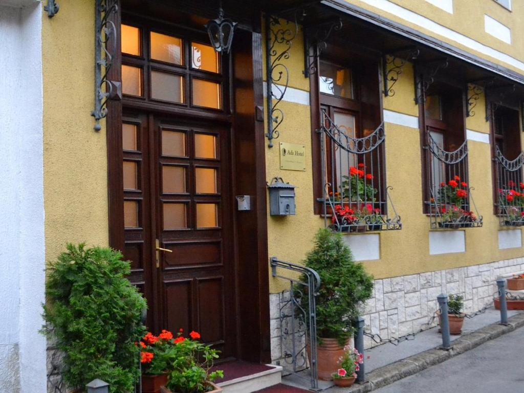 a building with a wooden door and flowers in pots at Ada Apartments in Sarajevo