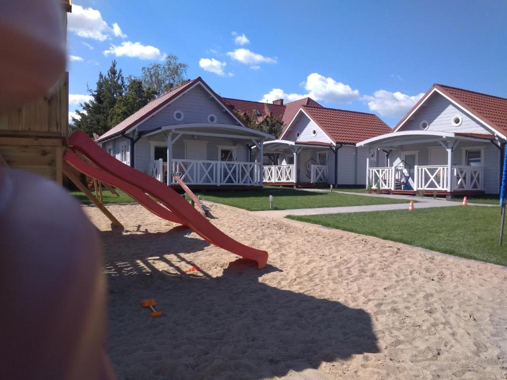 a playground with a slide in front of houses at Kotwicownia in Mikołajki