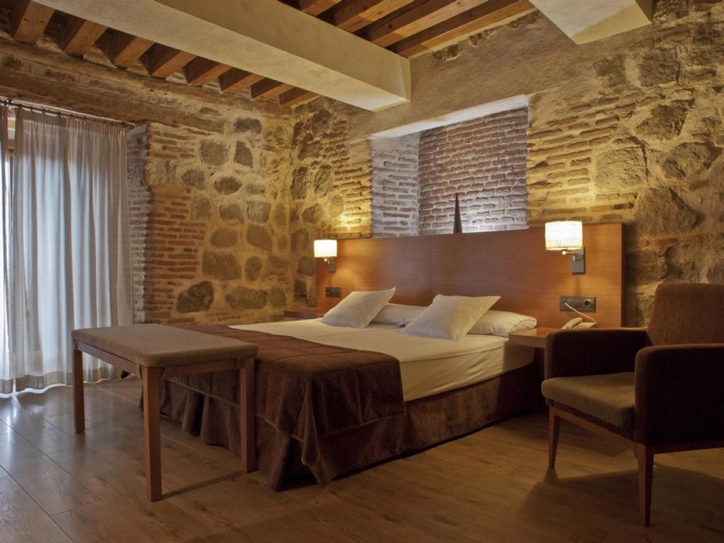 um quarto com uma cama grande numa parede de pedra em Hotel Las Leyendas em Ávila