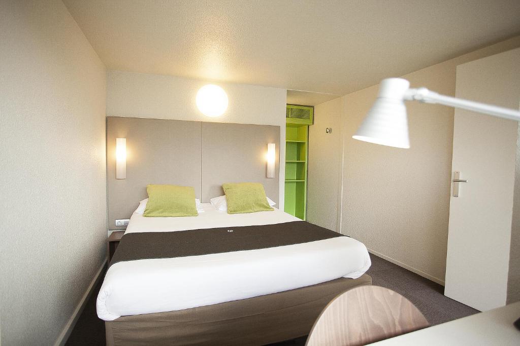 a bedroom with a large bed with green pillows at Campanile Pontarlier in Pontarlier