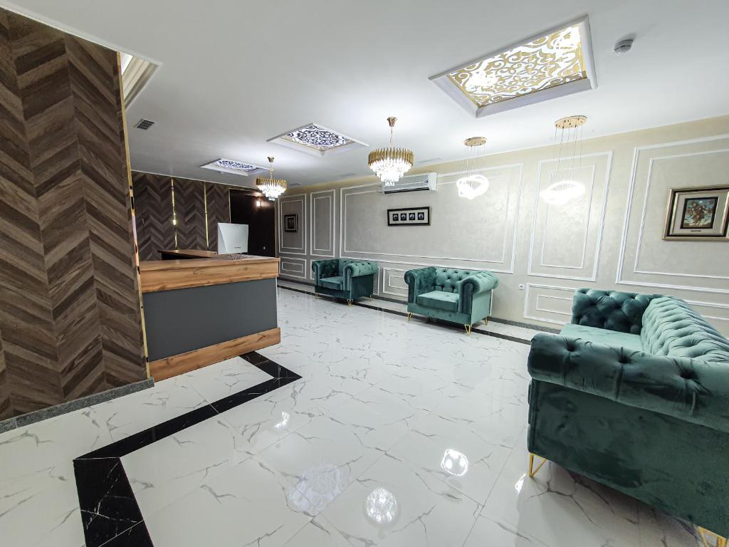 a waiting room with green chairs and a reception desk at Ritz Hotel in Atyraū