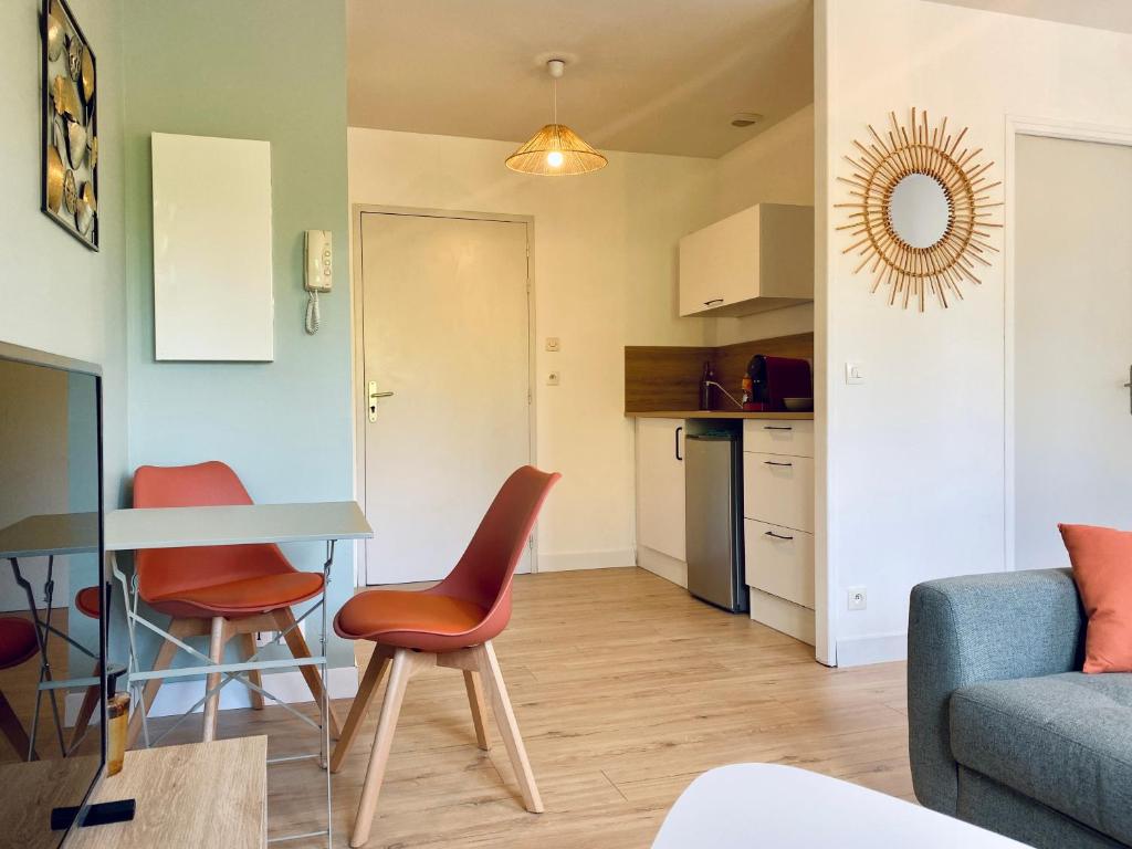 a kitchen and a living room with a table and chairs at Appartement proche Hôpital et centre-ville in Saint Lo