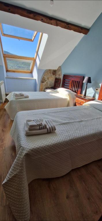Un dormitorio abuhardillado con dos camas y una claraboya. en Casa Cesar, en Lubián