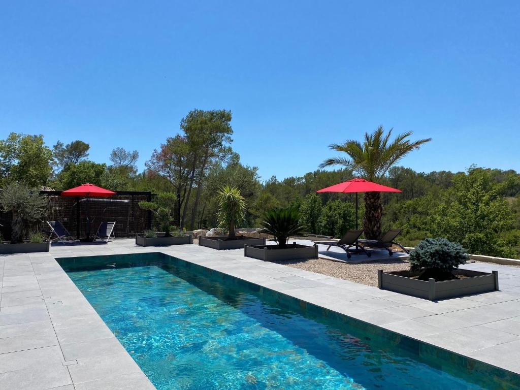 a swimming pool with two umbrellas in a yard at LES ROCHES DE BAUDISSET in Saint-Paul-en-Forêt