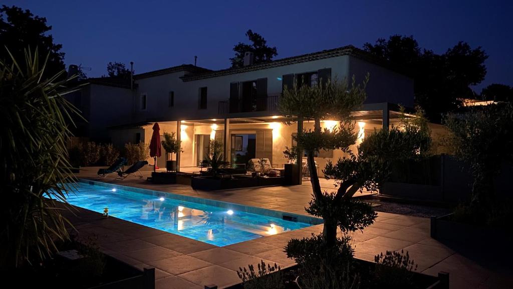 a swimming pool in front of a house at night at LES ROCHES DE BAUDISSET in Saint-Paul-en-Forêt