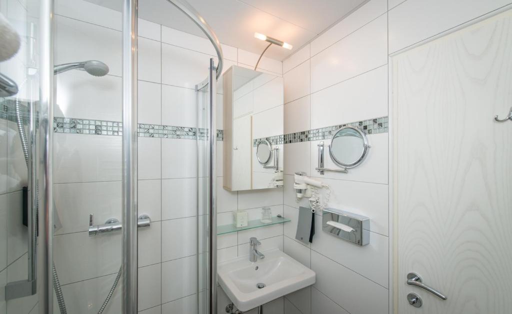 baño blanco con ducha y lavamanos en Hotel Boltzmann, en Viena