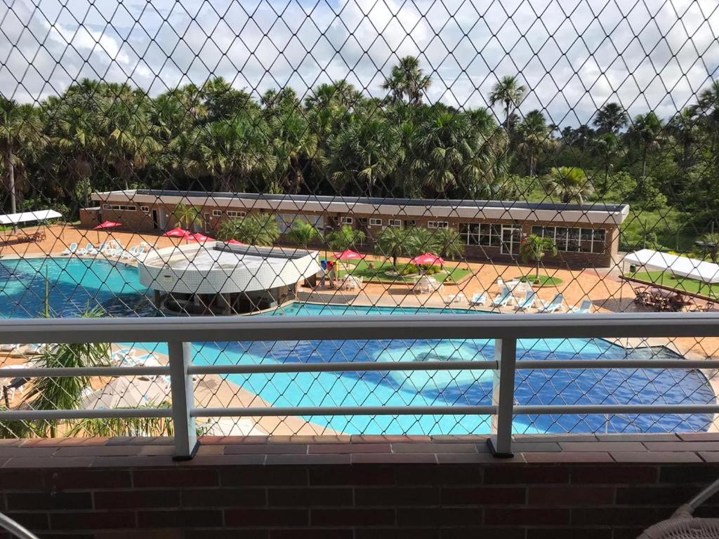 uma vista para uma piscina através de uma cerca em GRAN LENÇÓIS FLAT - APTO PARTICULAR em Barreirinhas