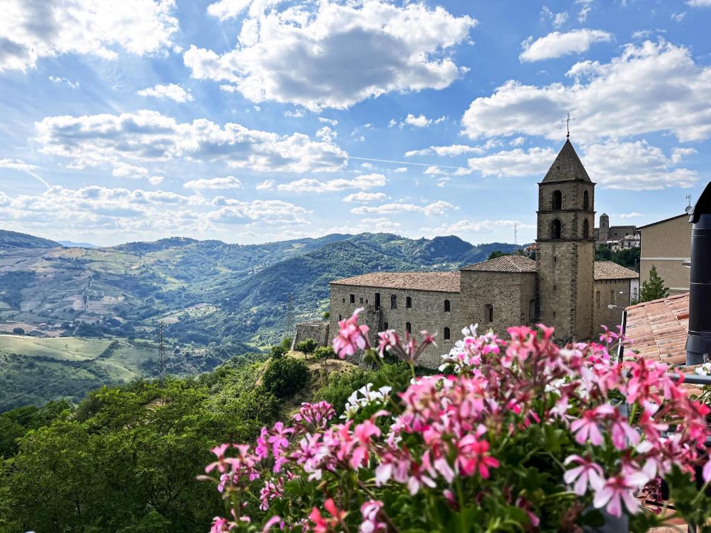 a building on a hill with flowers in the foreground at Residenza Sant'Angelo - Bike&Trekking House in Pietrapertosa