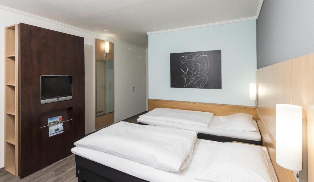 2 Betten in einem Zimmer mit einem TV an der Wand in der Unterkunft Good Morning Erfurt in Erfurt