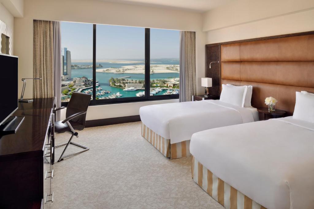 a hotel room with two beds and a large window at InterContinental Abu Dhabi by IHG in Abu Dhabi