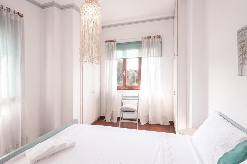 a white bedroom with a bed and a window at Stonehouse_ioa in Ioannina