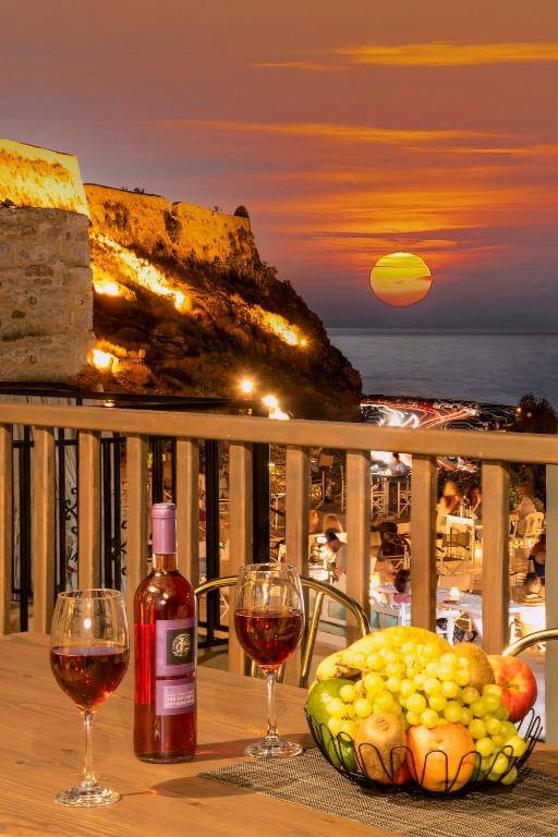 a table with two glasses of wine and a bowl of fruit at Fortezza Side Suite in Rethymno