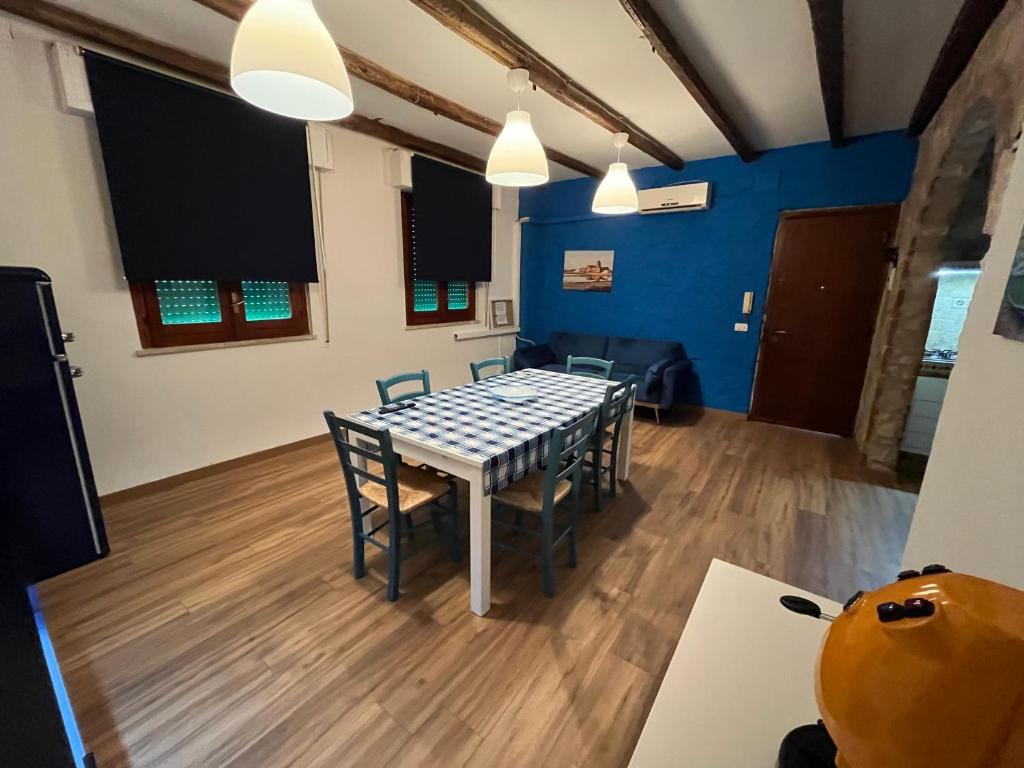 una mesa y sillas en una habitación con paredes azules en House Suite Sea en Isola delle Femmine