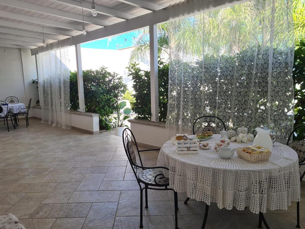 een witte tafel met stoelen op een patio bij Casa Poesia in Torre San Giovanni Ugento