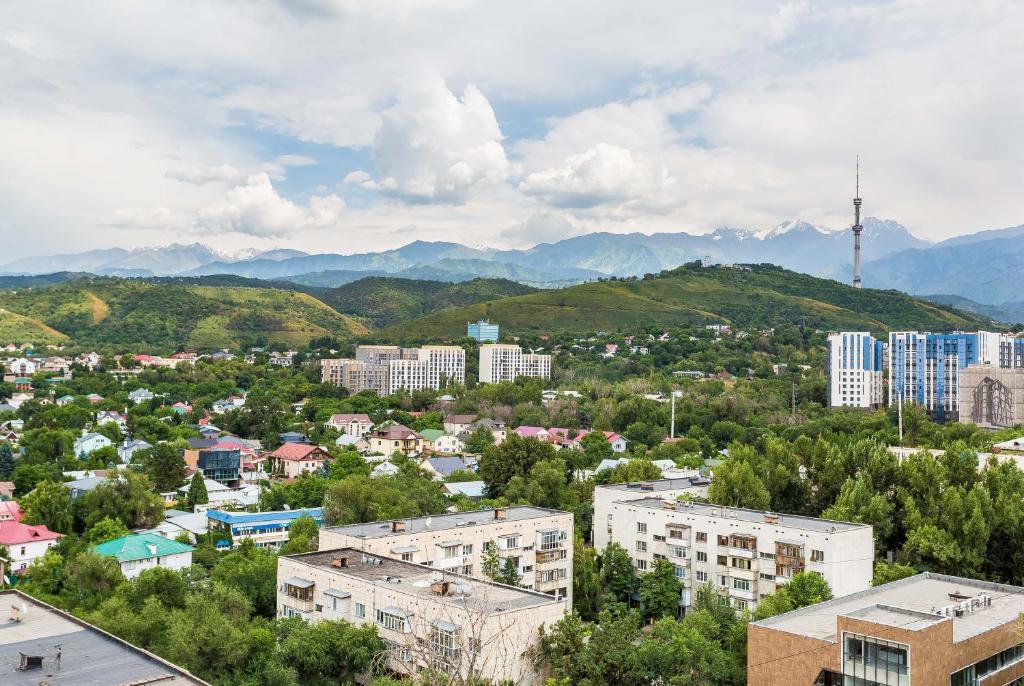 a city with buildings and mountains in the background at Золотой квадрат, центр Алматы! in Almaty