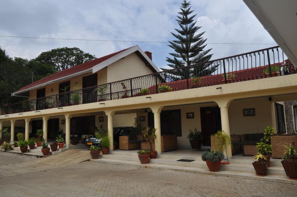 un grand bâtiment avec des plantes en pot devant lui dans l'établissement The Milimani Lodge, à Arusha