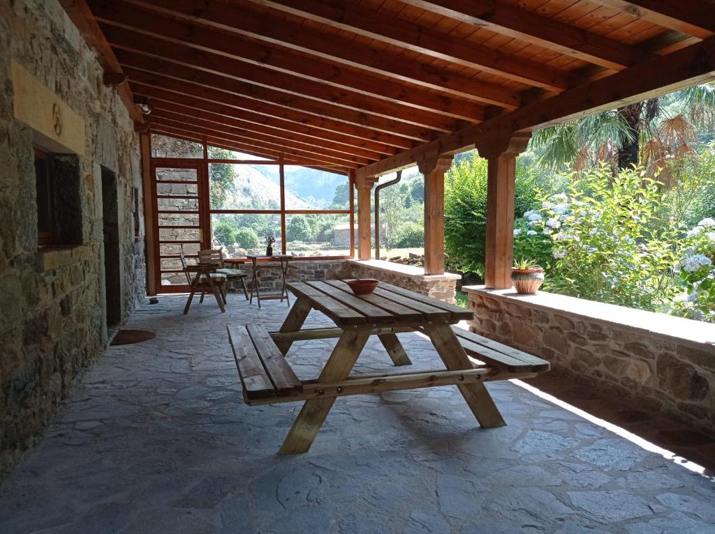 a wooden picnic table sitting on a patio at Amplia y cómoda casa de piedra con porche y jardín in San Roque de Ríomiera