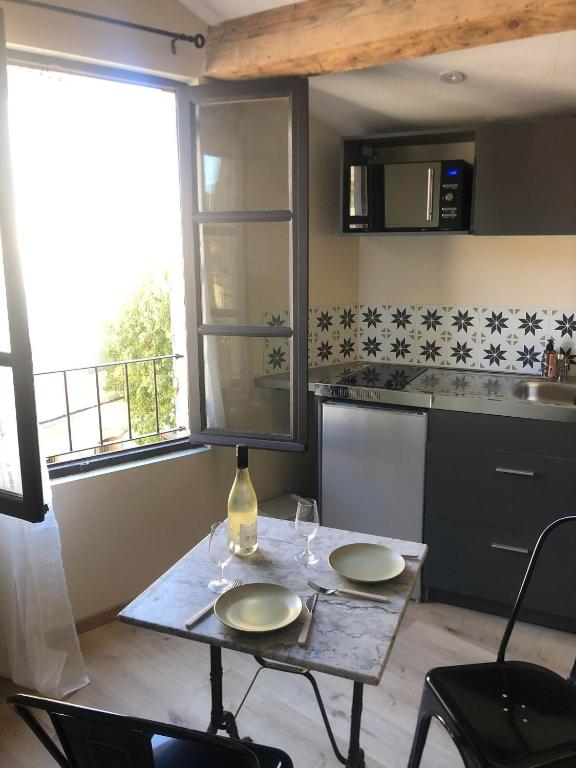 - une cuisine avec une table et 2 verres à vin dans l'établissement ARLES: Studio de la place, à Arles