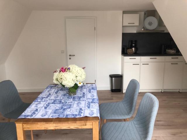 a table with chairs and a vase of flowers on it at Die Gräfin auf Rügen - Ferienappartements in Parchtitz