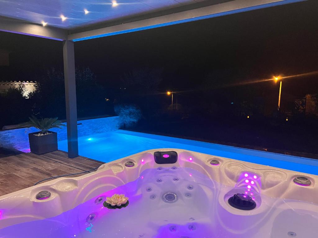 a jacuzzi tub on a patio at night at Suite romantique Le temps d'un Instant Loveroom Hammam jacuzzi piscine in Villeneuve