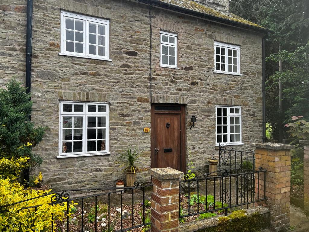 a stone house with a wooden door and windows at The nook 21a mill street in Kington