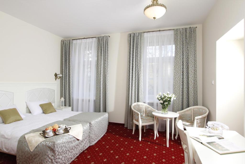 ルブリンにあるLawendowy Dworekのベッド、テーブル、椅子が備わるホテルルームです。