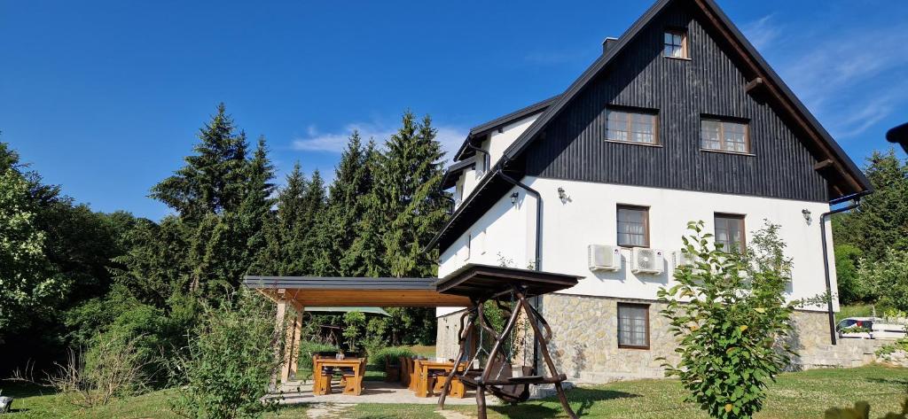 una casa con tetto a foglia d'azzardo e portico di Plitvice Inn a Jezerce